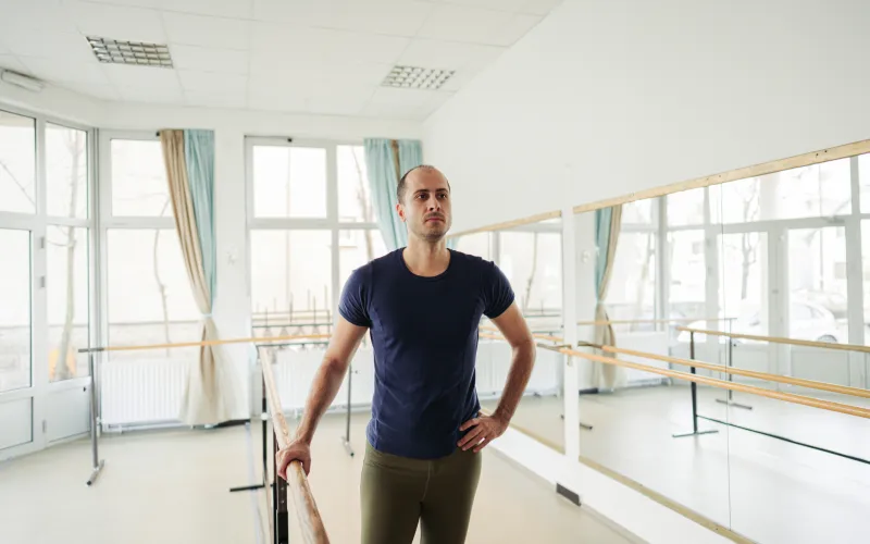 Een man van middelbare leeftijd met donker haar staat in een dansschool.