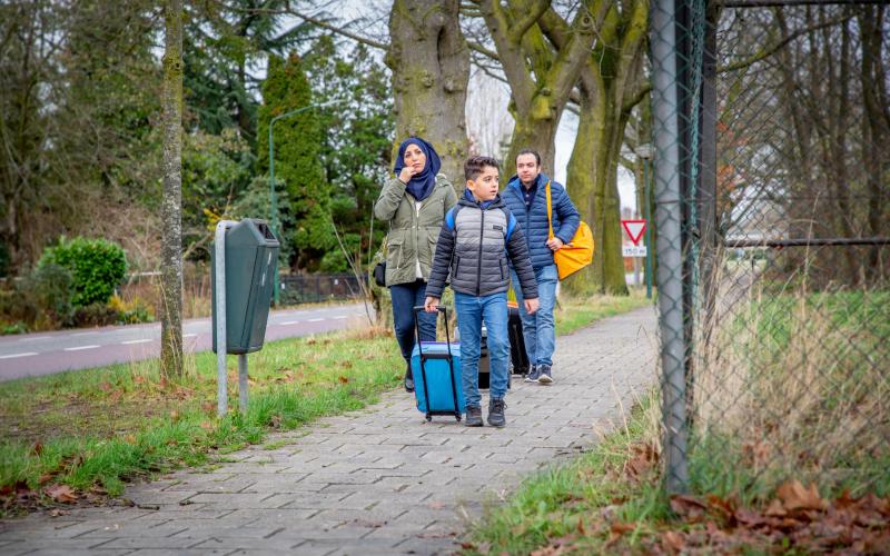Een gezin loopt langs het hek van een asielzoekerscentrum