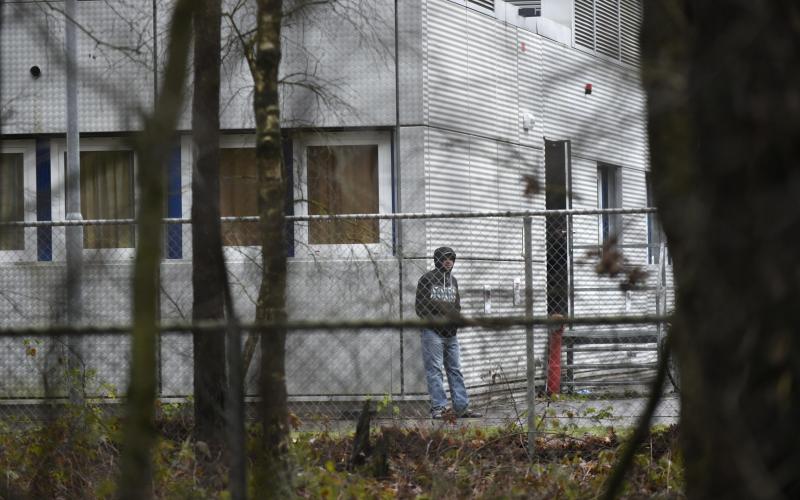 Asielzoeker staat bij een uitzetcentrum