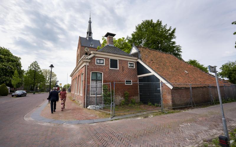 De Nationale ombudsman loopt door een straat in Groningen. Schade van de aardbeving is zichtbaar aan huizen.