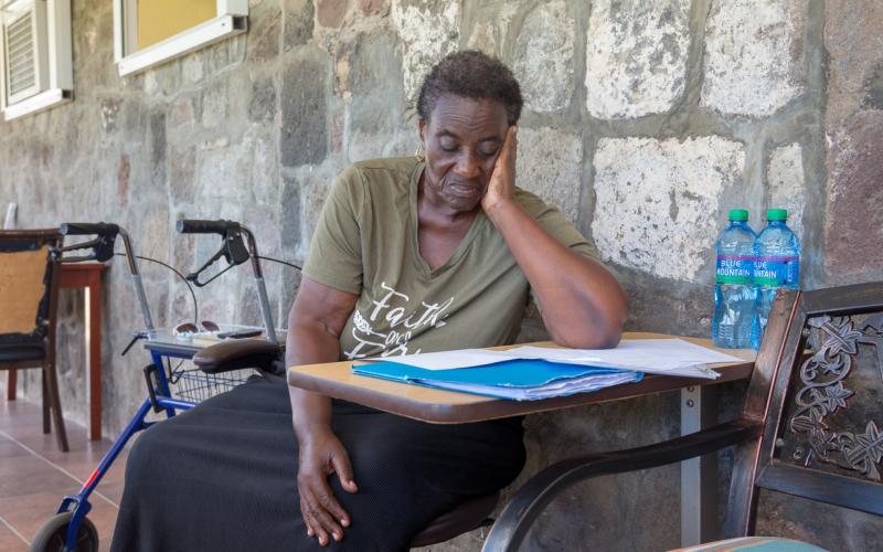 Caribische vrouw zit aan tafel en leest een brief