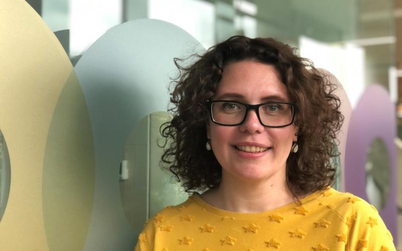 Vrouw met donker krullend haar (Caroline Luttmer, Nationale ombudsman). Ze draagt een donkere bril en gele jurk Vrouw met donker krullend haar (Caroline Luttmer, Nationale ombudsman). Ze draagt een donkere bril en gele jurk