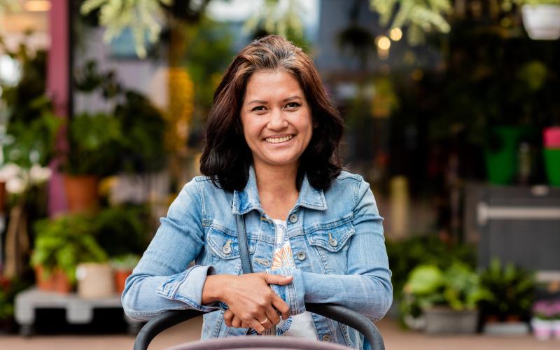 Cora, een vrouw van middelbare leeftijd met bruin haar en een spijkerjasje aan. Ze leunt op een kinderwagen. Cora, een vrouw van middelbare leeftijd met bruin haar en een spijkerjasje aan. Ze leunt op een kinderwagen.