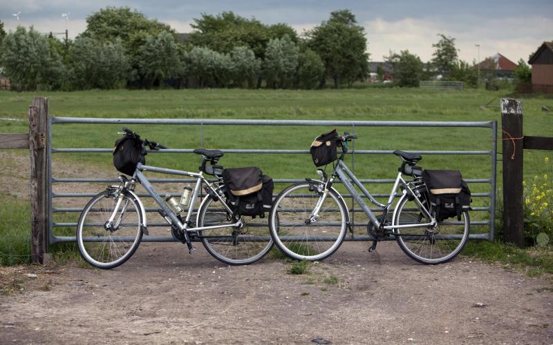 Twee fietsen tegen een hek bij weiland