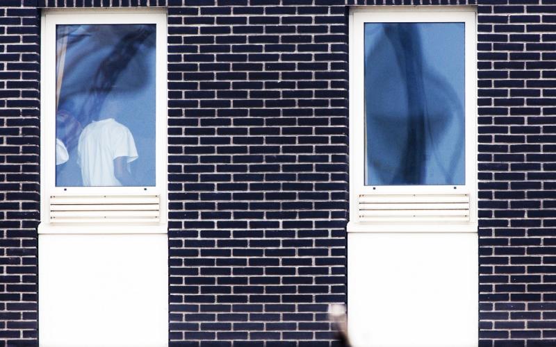 man staat bij raam van detentiecentrum man staat bij raam van detentiecentrum