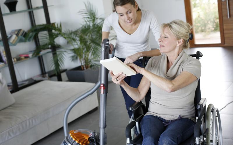 thuiszorg, vrouw zit in rolstoel en is in gesprek met hulp