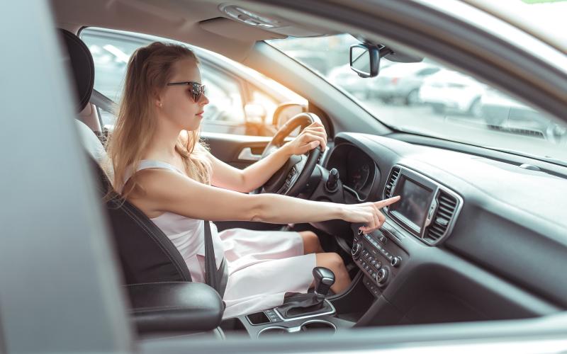 Vrouw in auto toetst in op boordcomputer Vrouw in auto toetst in op boordcomputer