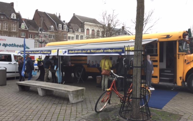 Foto van de gele Ombudsbus van de Nationale ombudsman op de markt in Limburg