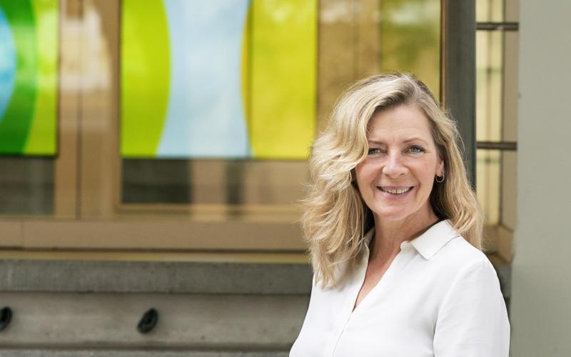 Blonde vrouw (Jeanine Stam, onderzoeker Nationale ombudsman) kijkt lachend in de camera. Ze draagt een wit shirt.