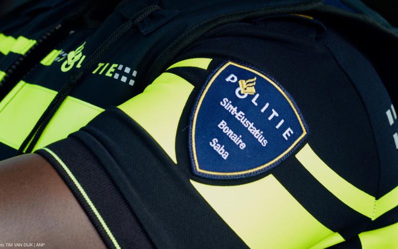 Foto van de mouw van politiekleding met op de mouw gespeld Politie Sint-Estatius, Bonaire en Saba