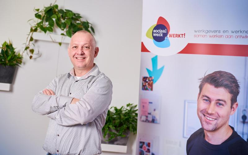 Lachende man (Marcel van Eck), kort grijs haar en gestreept overhemd. Armen over elkaar gekruist Lachende man (Marcel van Eck), kort grijs haar en gestreept overhemd. Armen over elkaar gekruist