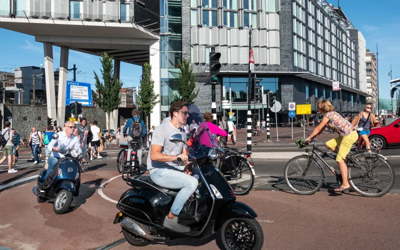 Zomerse dag, mensen op de fiets, scooter en wandelend over straat