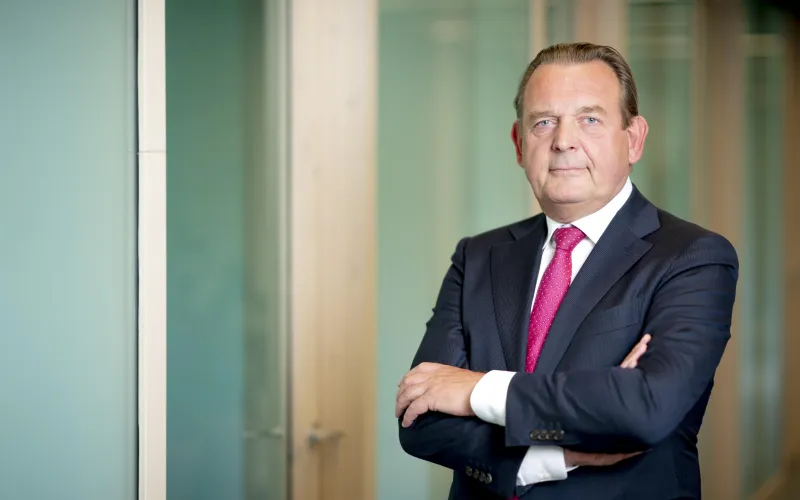 Man (Reinier van Zutphen, Nationale ombudsman) draagt donker blauw pak en rode stropdas. Beide handen zijn gekruist