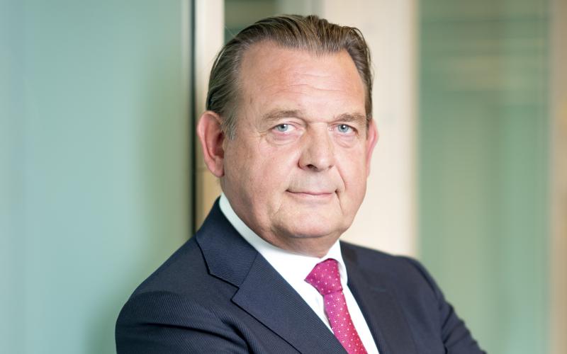 Man (Reinier van Zutphen, Nationale ombudsman) draagt donker blauw pak en rode stropdas. Hij leunt tegen de wand Man (Reinier van Zutphen, Nationale ombudsman) draagt donker blauw pak en rode stropdas. Hij leunt tegen de wand