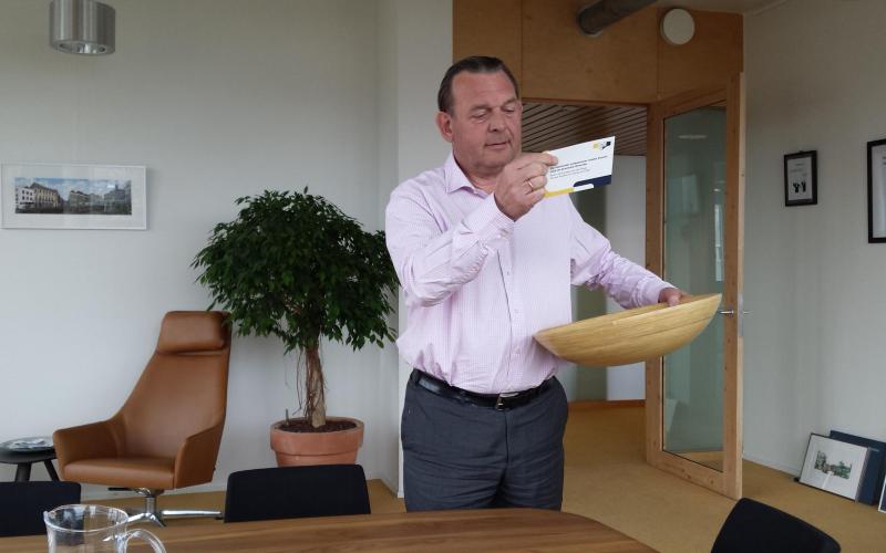 Foto van Nationale ombudsman Reinier van Zutphen die een winnaar trekt uit alle feedbackkaartjes die zijn opgehaald tijdens zijn tour naar Drenthe