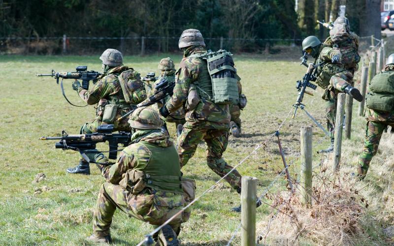Een groep militairen loopt door een wei Een groep militairen loopt door een wei