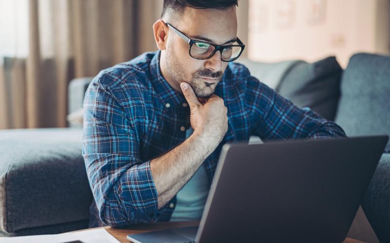 Man kijkt zorgelijk op laptop Man kijkt zorgelijk op laptop