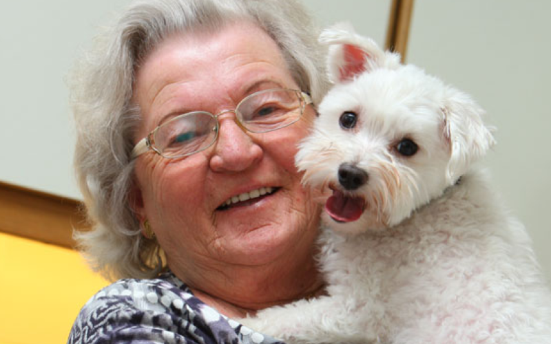 lachende dame op leeftijd met hond op de arm