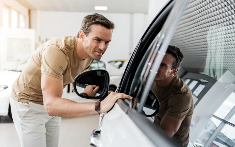 man staat voorovergebogen bij auto