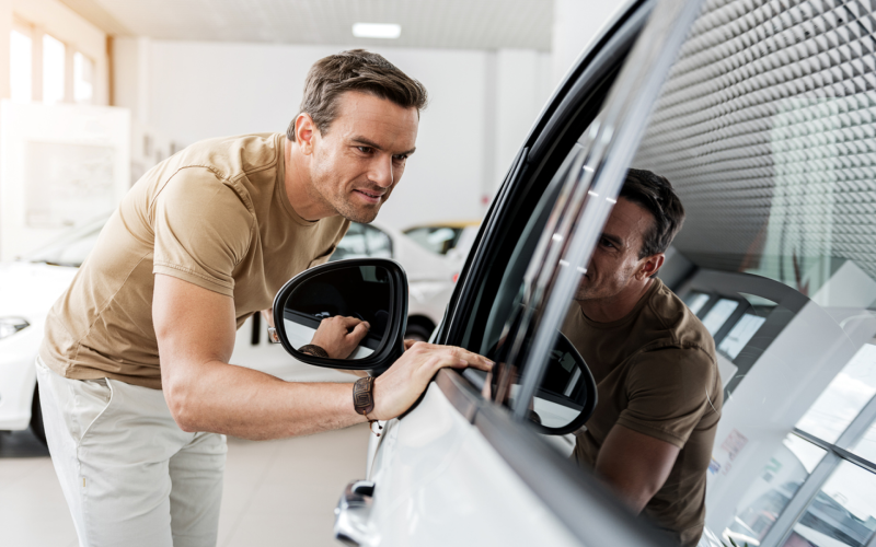 man staat voorovergebogen bij auto