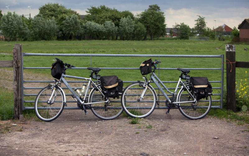 Foto van twee fietsen bij een hek