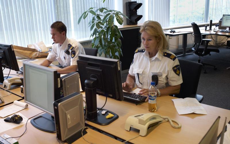 Foto van politieagenten achter een computer