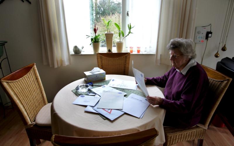 Foto van een vrouw aan tafel met papieren