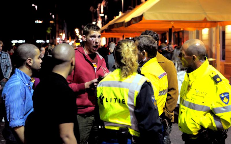 Agenten en groep mannen op straat, man is gewond Agenten en groep mannen op straat, man is gewond
