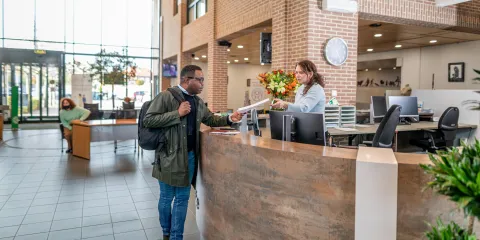 Een man staat bij de balie op het gemeentekantoor