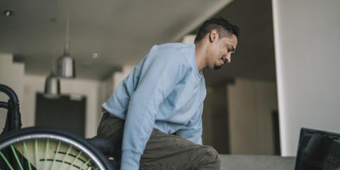 Een man verplaatst van zijn rolstoel naar de bank