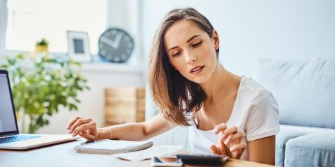 Vrouw zicht aan een tafel en heeft een rekenmachine en notitieblok voor zich