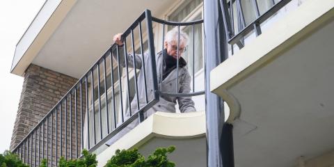 Oudere man houdt trailiewerk vast bij appartement 