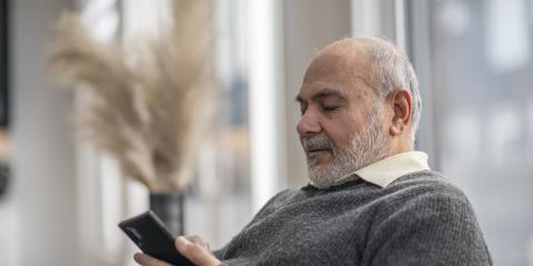 Oudere man op de bank met telefoon