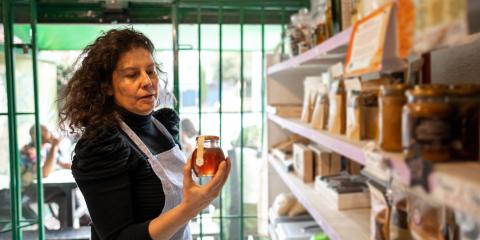Vrouw werkzaam in een winkel heeft een pot honing vast