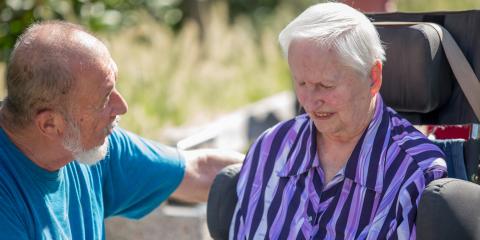 Oudere vrouw met in rolstoel met haar man naast haar