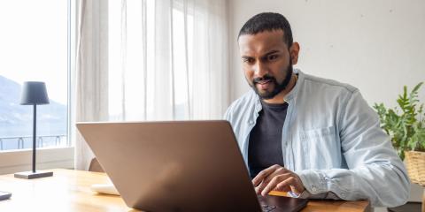 Jongvolwassen man zit achter zijn laptop