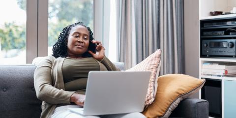 Vrouw zit op de bank met laptop op schoot
