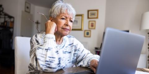 Oudere vrouw zit achter haar laptop