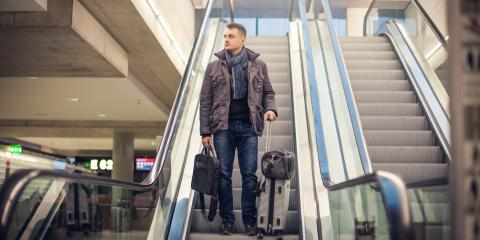 Man staat met een bagage op een roltrap op een vliegveld