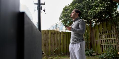 Jongeman staat in de tuin met een telefoon in zijn hand