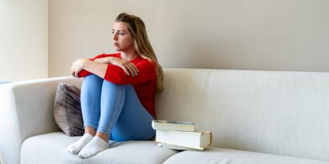 Jonge vrouw zit op de bank en is verdrietig