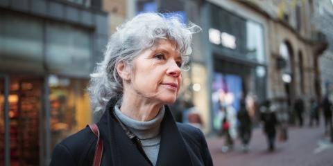 Oudere vrouw staat in een winkelstraat