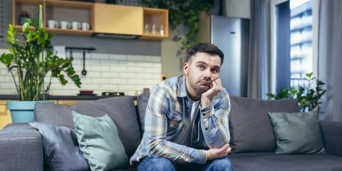 Man zit op de bank en baalt van een foutieve WOZ berekening van zijn huis 