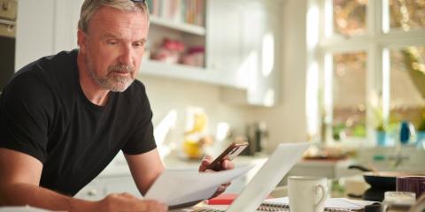 Man aan tafel met papieren, kijkt bezorgd