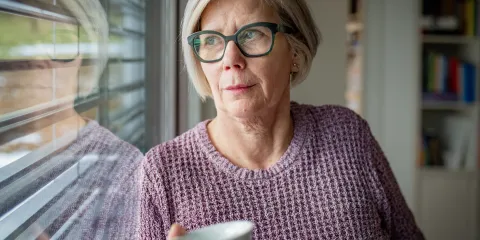 vrouw kijkt uit raam naar balkon