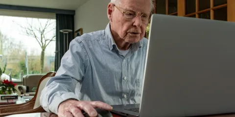 man zit achter een laptop