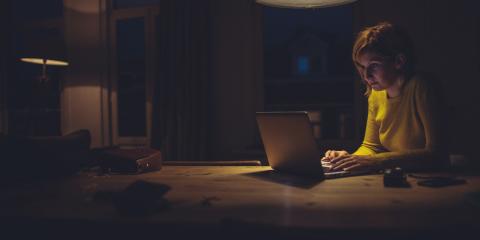 vrouw zit achter laptop in een donkere ruimte