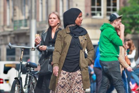 Vrouw met hoofddoek staat op straat en kijkt om zich heen