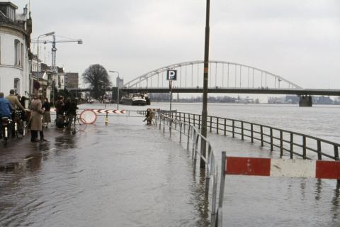 Straat staat onder water. Op de achtergrond staat een brug