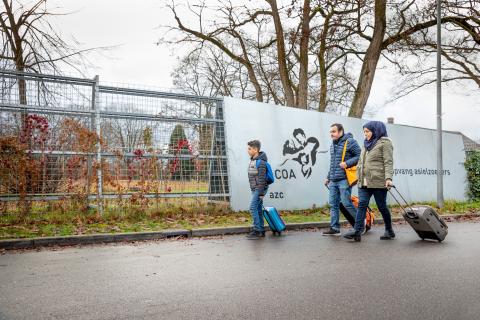 Drie mensen lopen langs de hekken van het COA